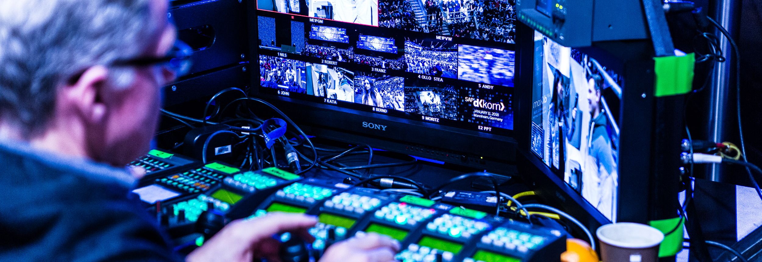 Techniker steuert Bild- und Tonmischung an einem Kontrollpult mit mehreren Monitoren.